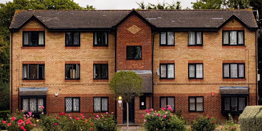 Three-story brick apartment building with rose bushes out front